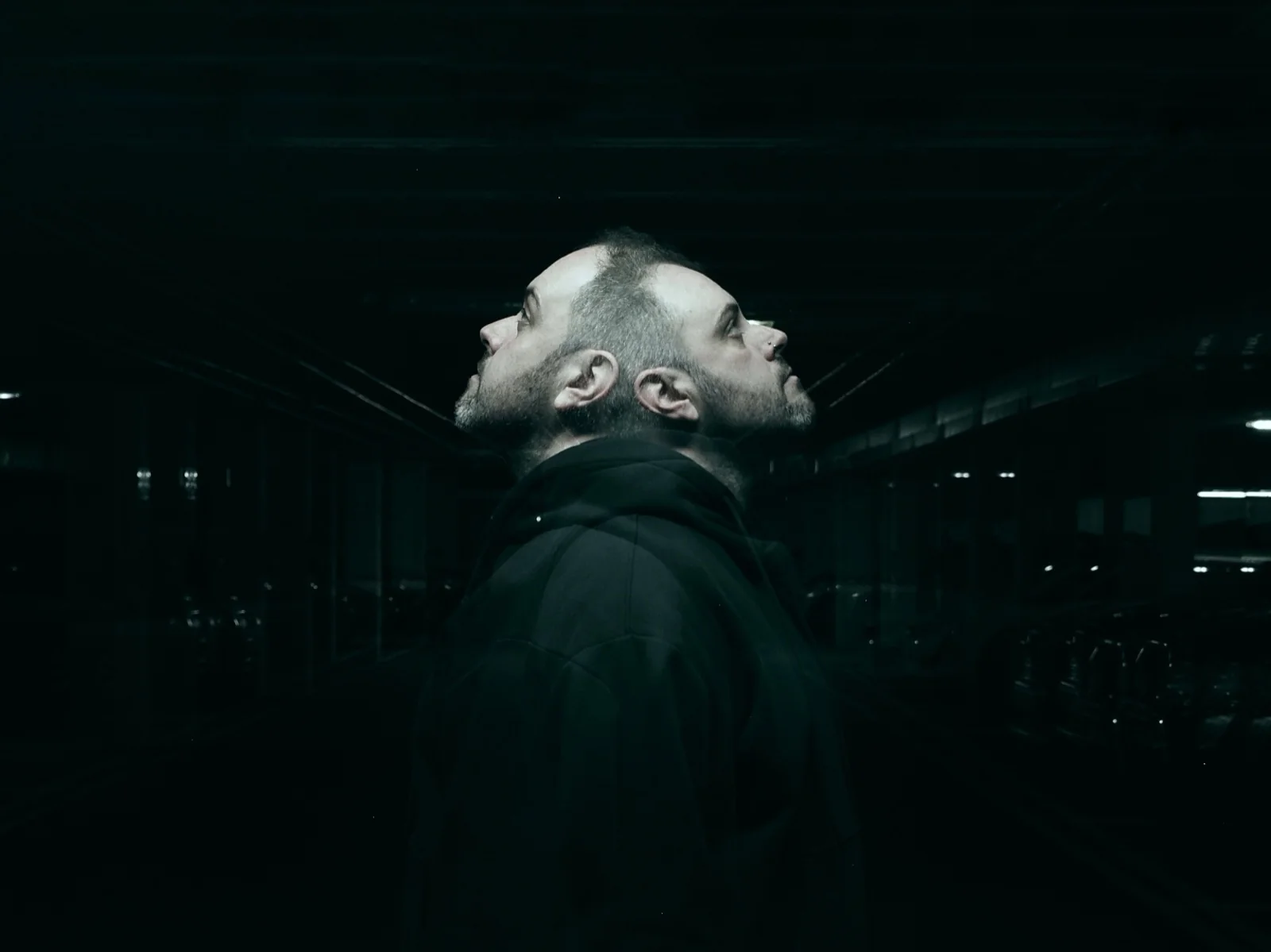 A figure looking upward in a dark corridor